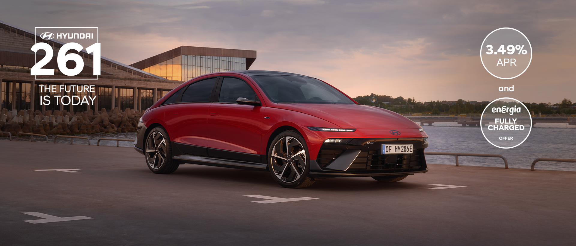 Hyundai IONIQ 6 electric sedan shown from the side parked on a city street with high rise buildings.