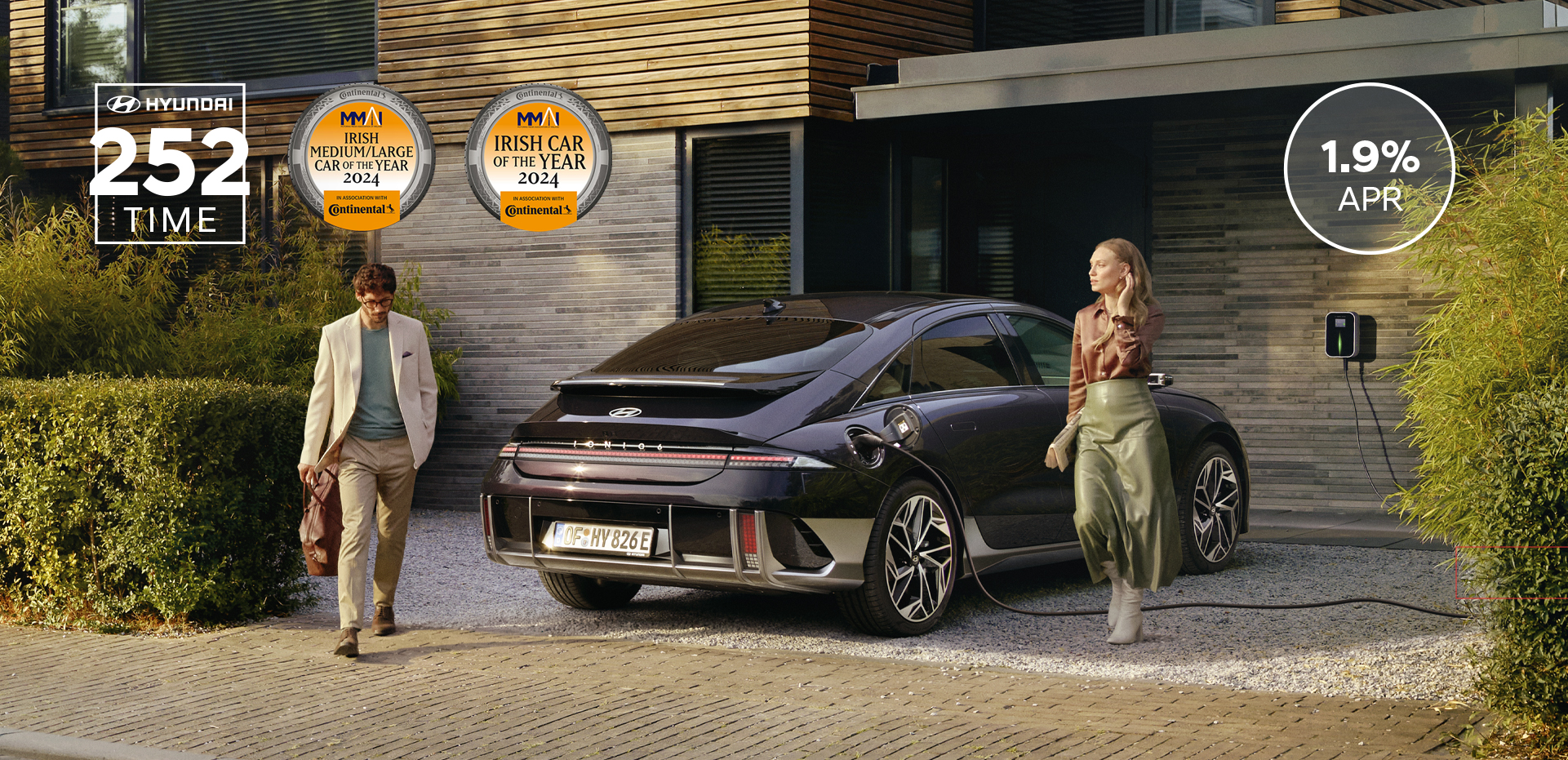The all-electric Hyundai IONIQ 6 charging in a city with a man leaning on it with an ice cream.
