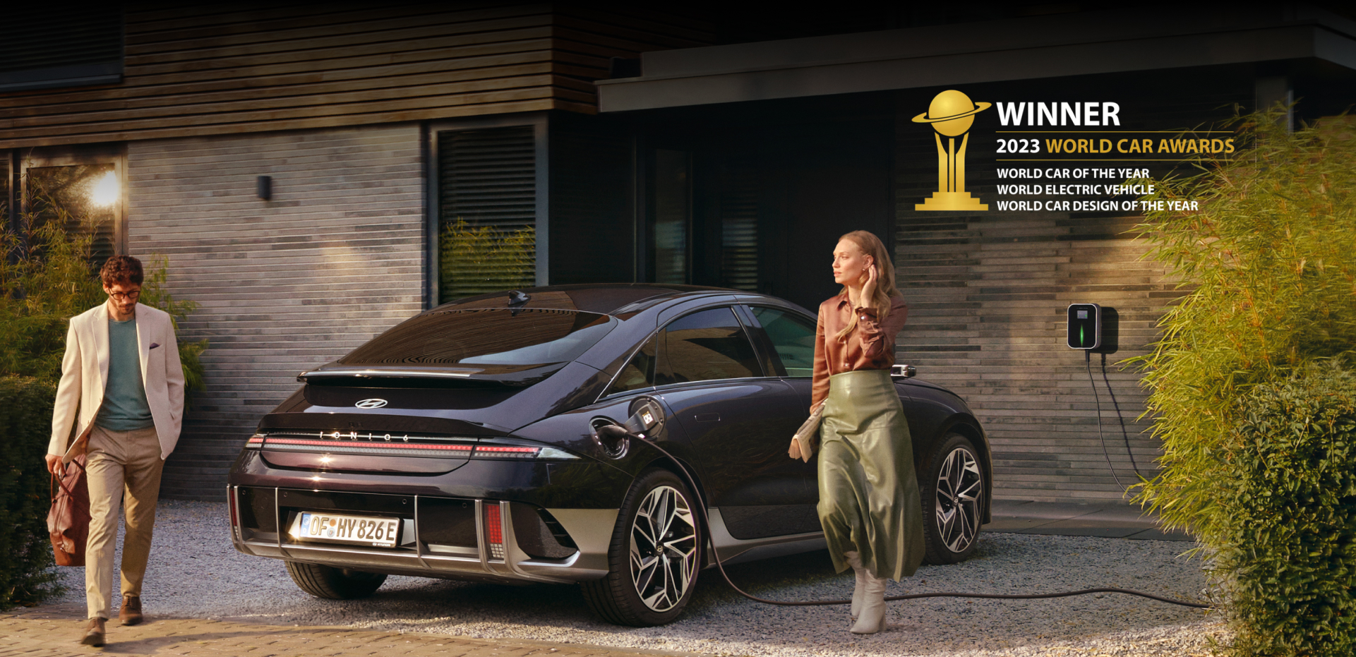 The all-electric Hyundai IONIQ 6 charging in a city with a man leaning on it with an ice cream.