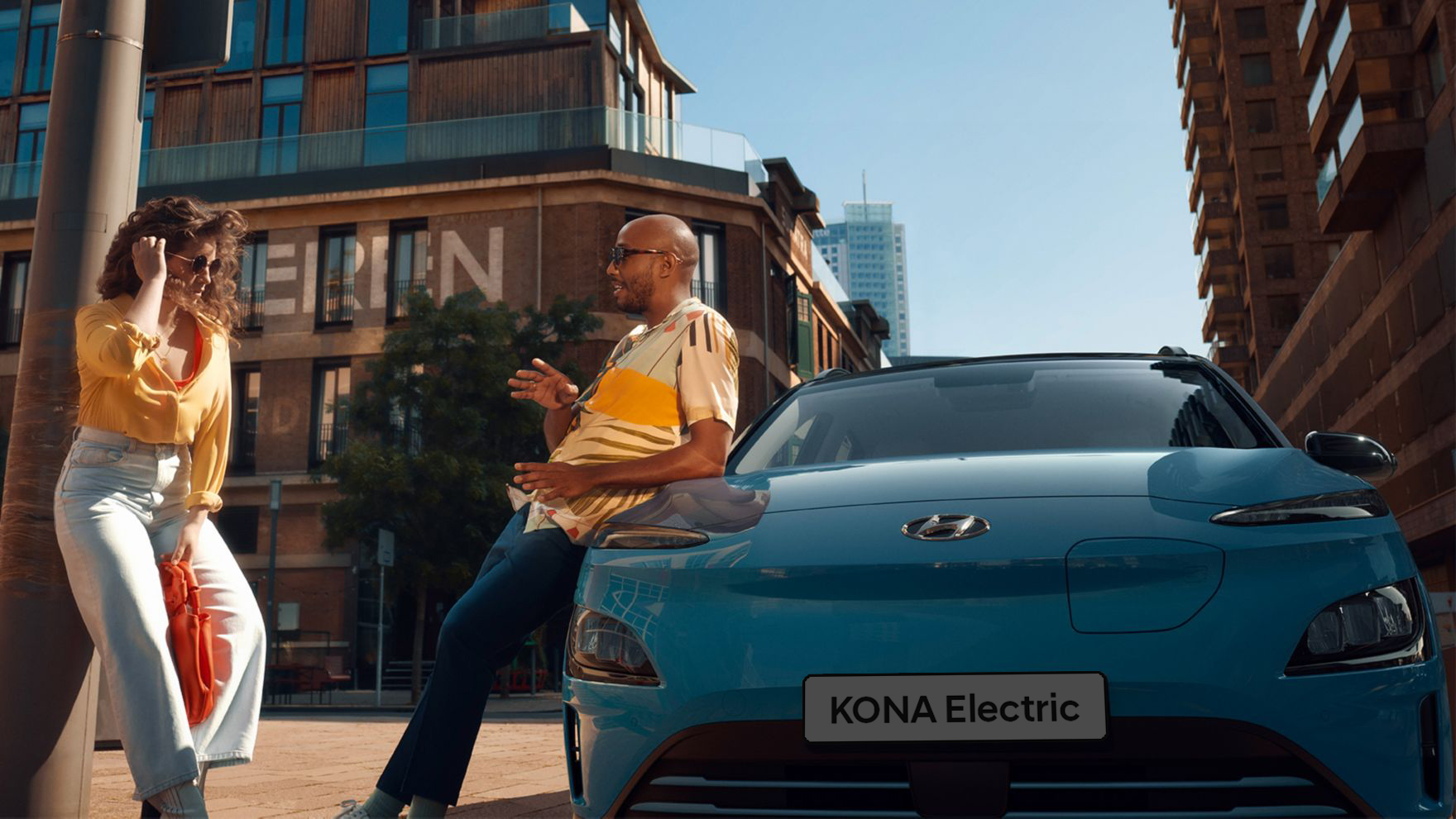 A man leaning against the new Hyundai Kona Electric talking to his friend.