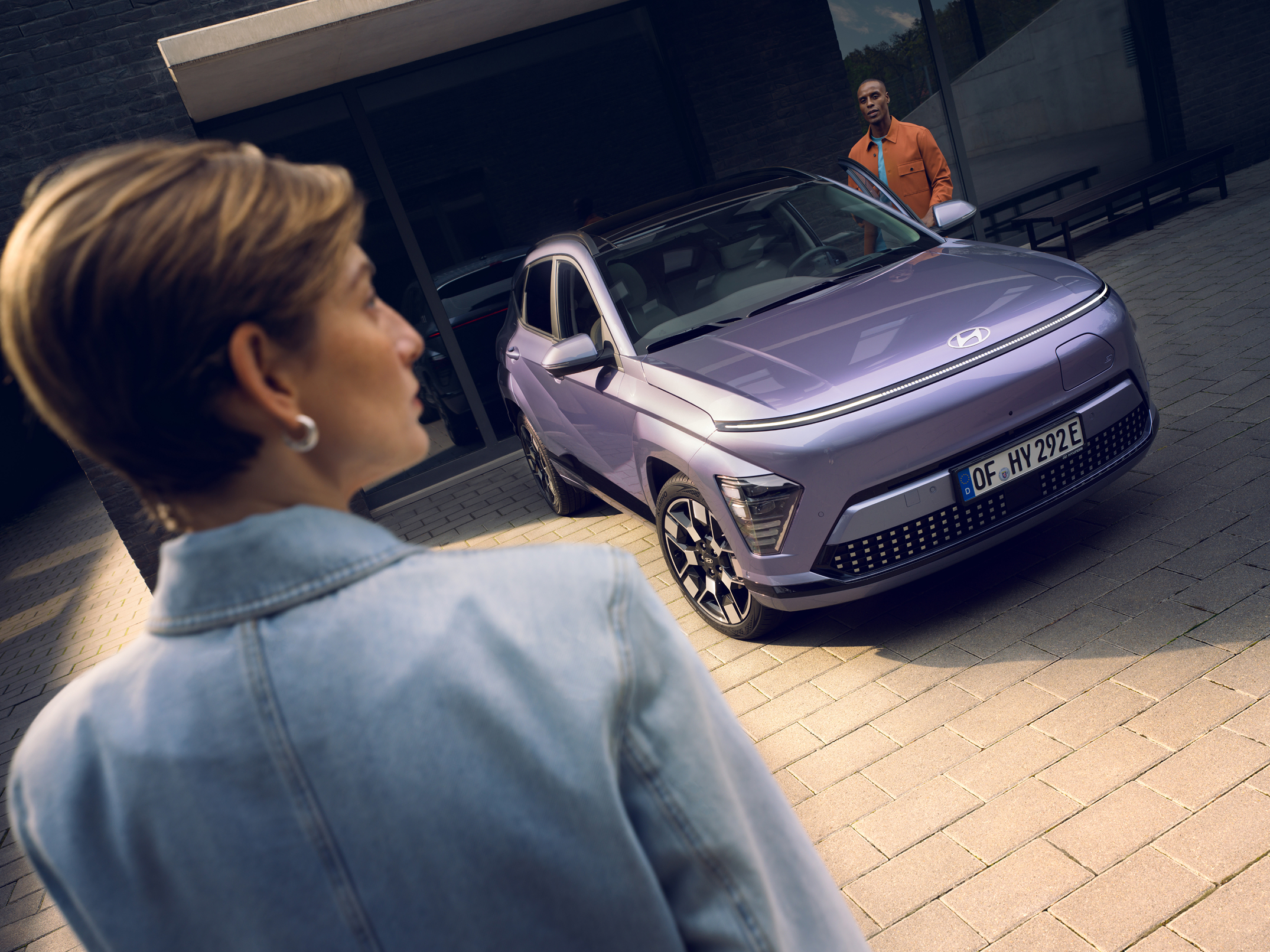The all-new Hyundai KONA Electric in blue with a woman in front of it.