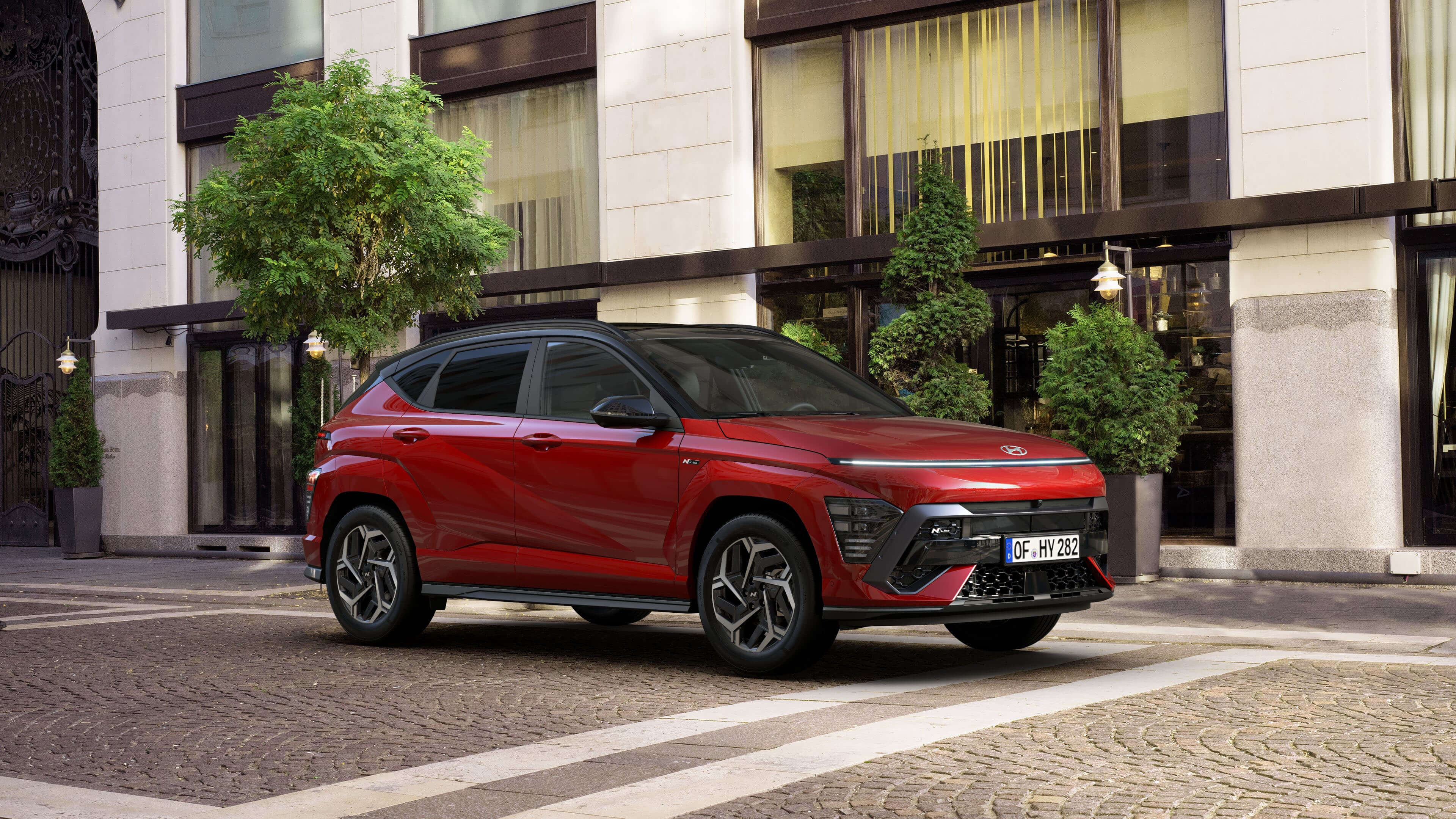 The new KONA N Line in red parked next to a modern building.