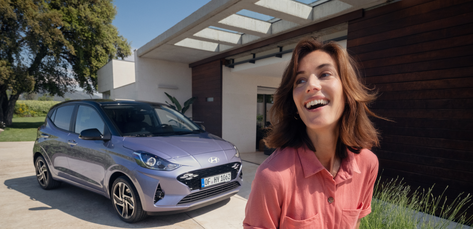 A woman walking and smiling in front of the new Hyundai i10.