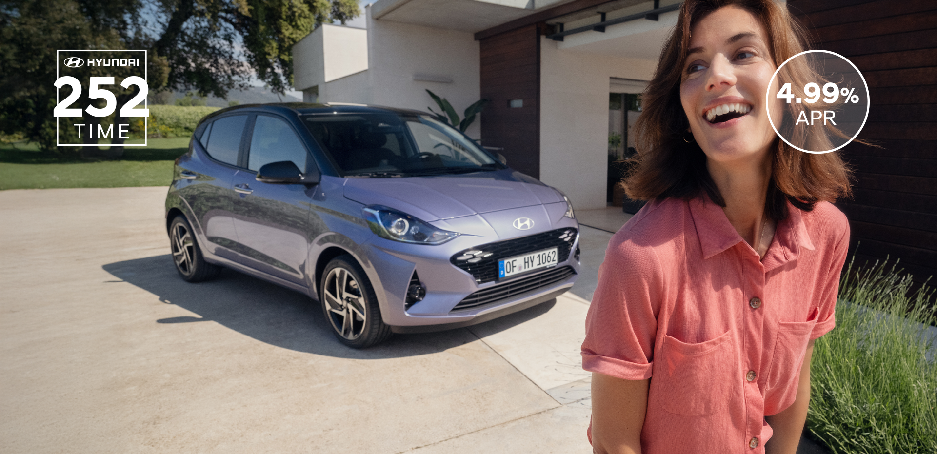 A woman walking and smiling in front of the new Hyundai i10.