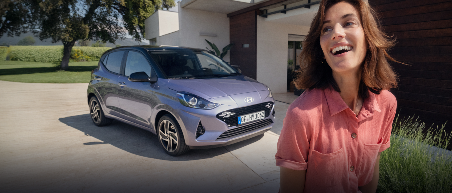 A woman walking and smiling in front of the new Hyundai i10.