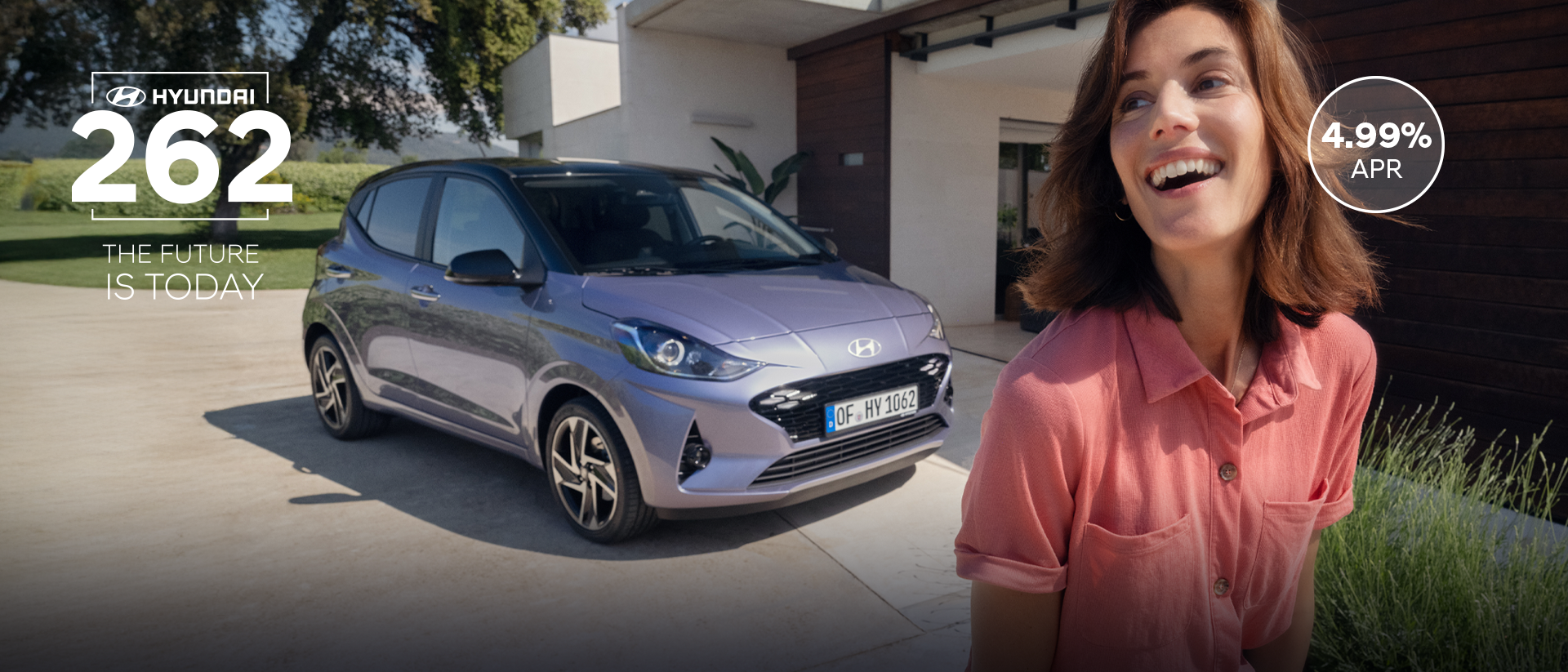 A woman walking and smiling in front of the new Hyundai i10.