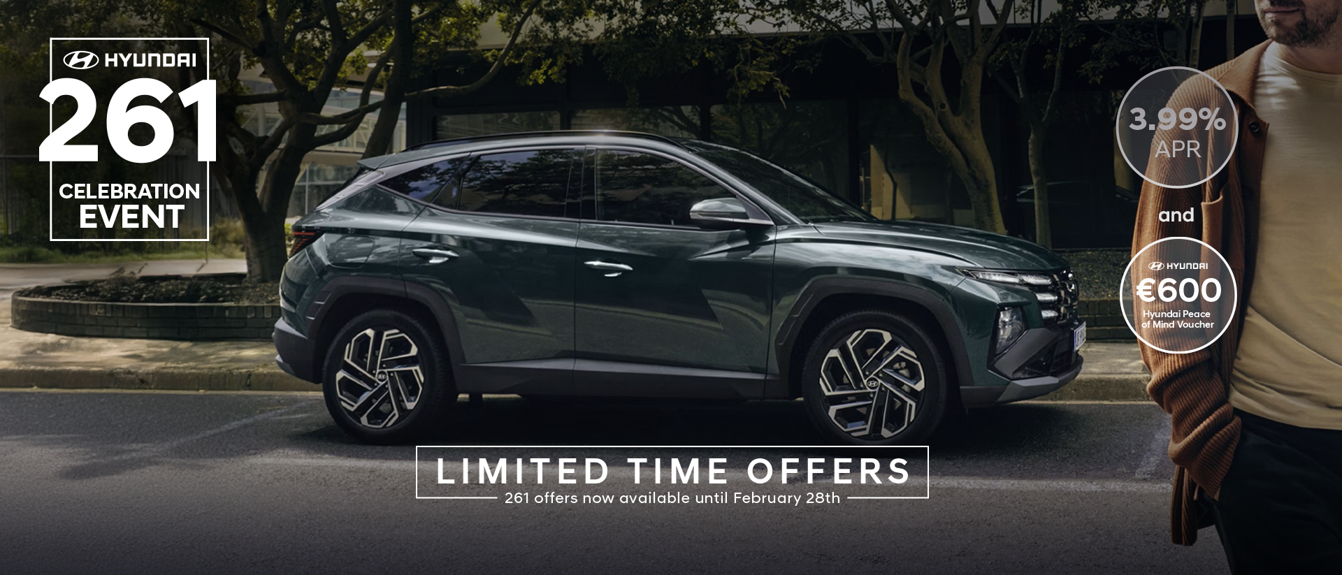A man walking near a Hyundai&nbsp;TUCSON Hybrid parked by some trees.