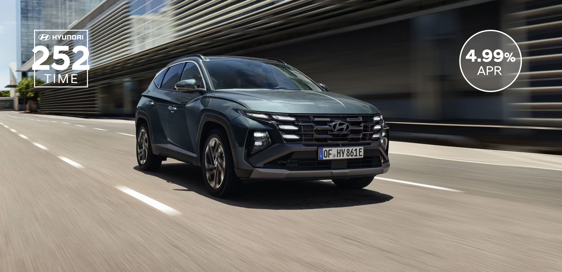 The Hyundai TUCSON Plug-in Hybrid driving down a city street with modern buildings visible.