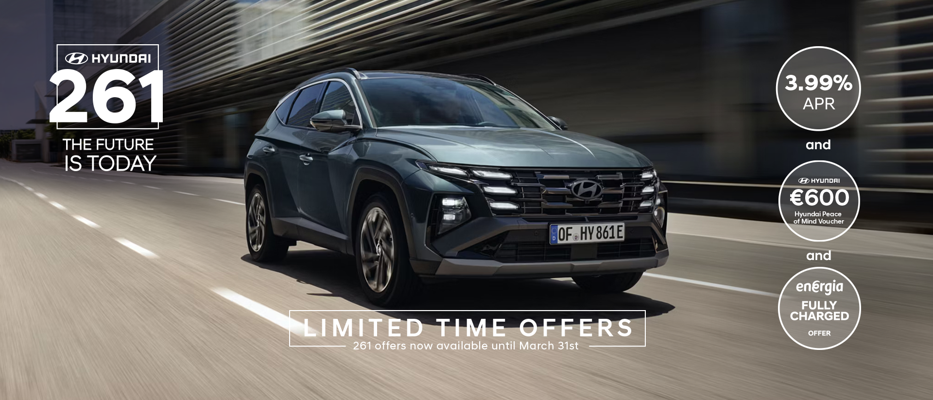 The Hyundai TUCSON Plug-in Hybrid driving down a city street with modern buildings visible.